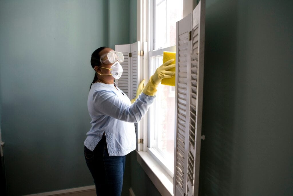 woman cleaning mold from window